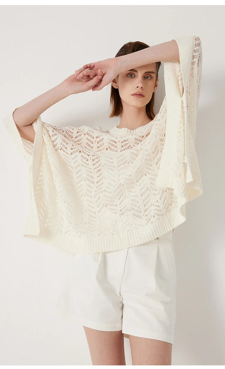 Model in Pearl Bush linen lace poncho with arms raised and fingers crossed, revealing openness of knit and quiet lightness. From Borcelleclothes.