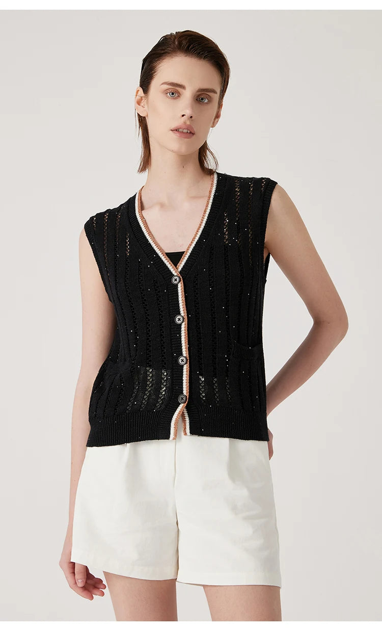 Close view of black linen vest with one hand on hip, emphasizing the lace texture and patch pocket detail. From Borcelleclothes.