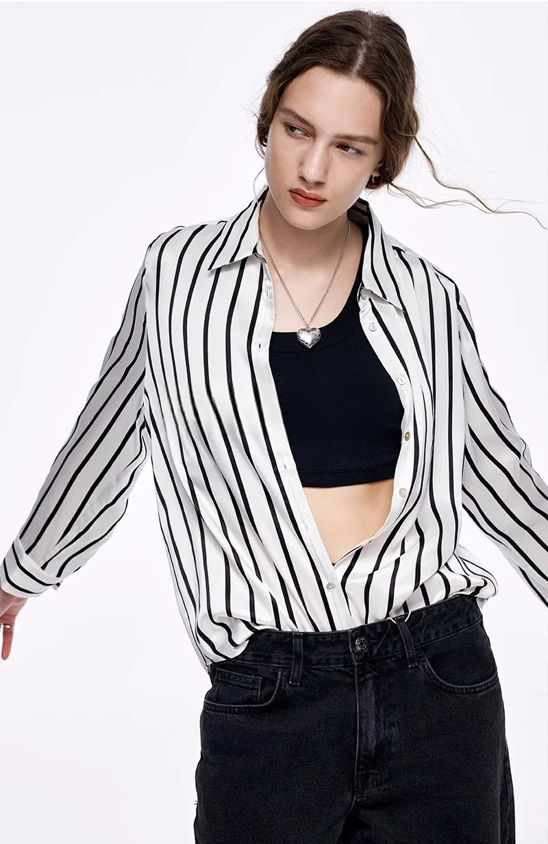 Model stretching her arms while wearing the unbuttoned Women's Luxury 6A Mulberry Silk Shirt in Striped Black & White, emphasizing the soft and flexible silk fabric. From Borcelleclothes.