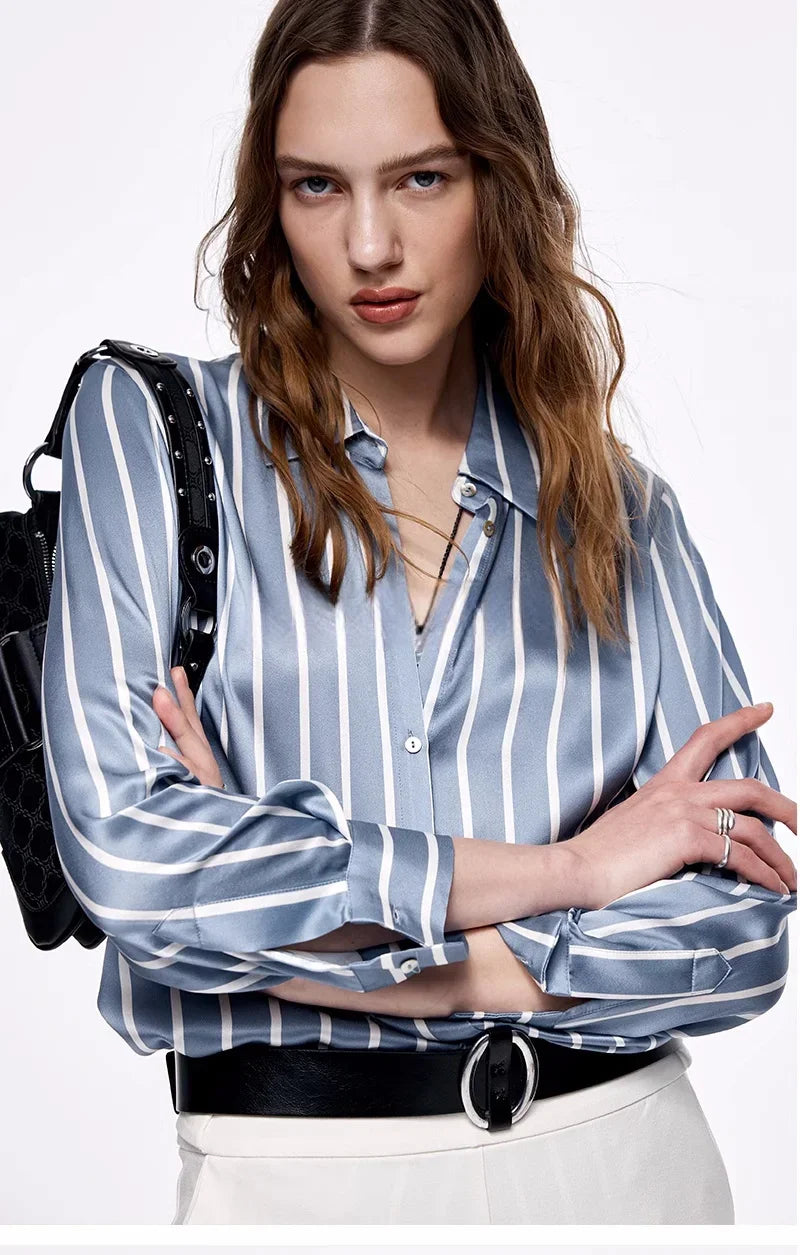 Model with crossed arms wearing Women's Luxury 6A Mulberry Silk Shirt in Striped Light Blue Grey & White, displaying the chic, relaxed silhouette. From Borcelleclothes.