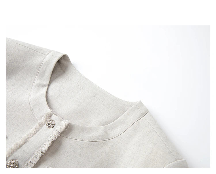 Detail view of the jacket’s round neckline and fringe-finished placket in the Martini set. From Borcelleclothes.