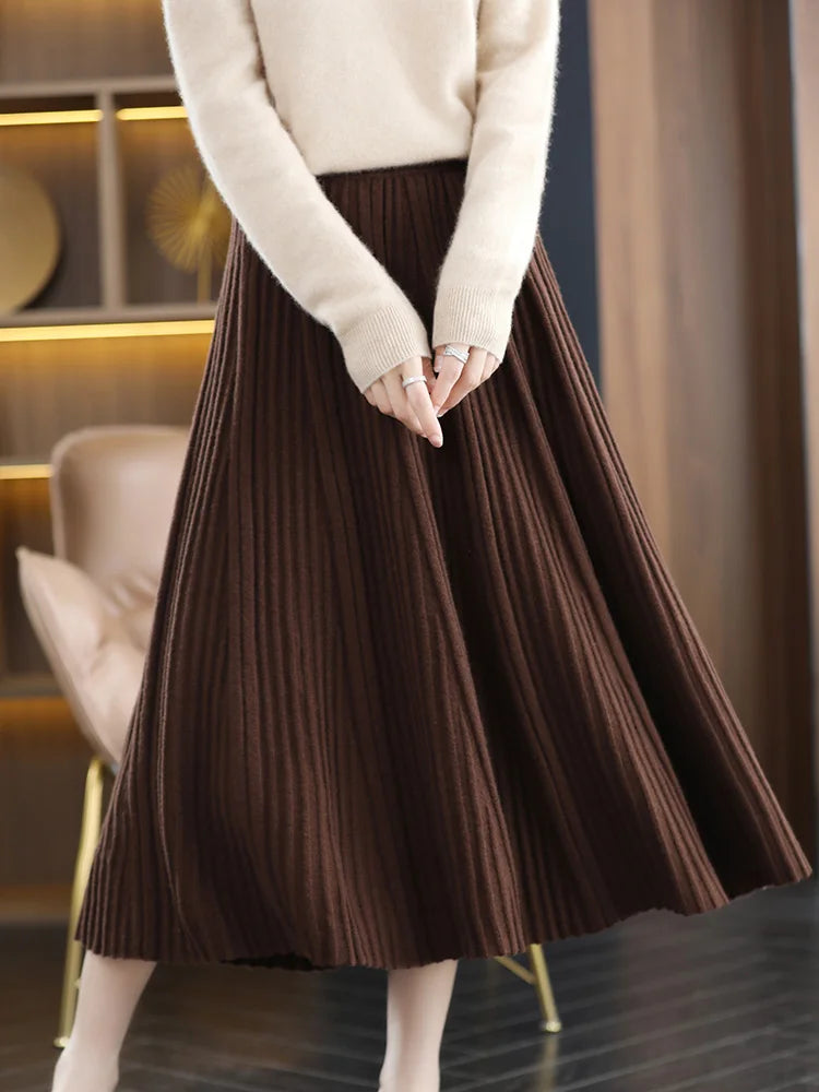 Model wearing merino skirt with textured pleats in Royal Brown, gently touching her fingers — From Borcelleclothes.