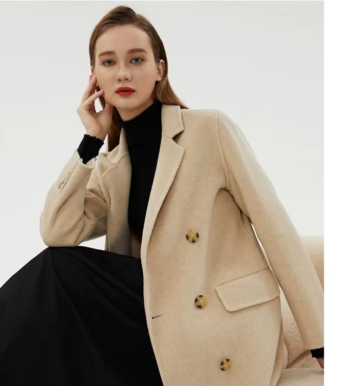 Model sitting on a sofa in the Women's Minimalist Long Wool Coat in Vanilla, showcasing its relaxed yet elegant silhouette. From Borcelleclothes.