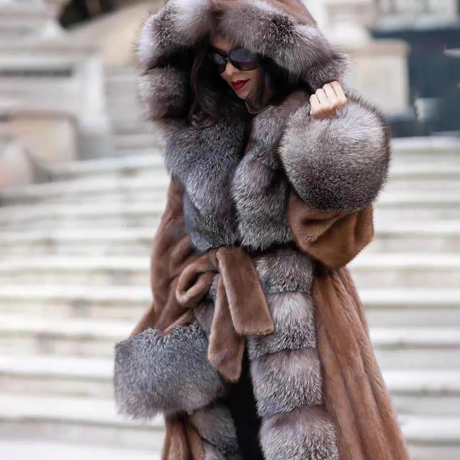 A close-up of a model wearing a Women's Mink & Crystal Fox Fur Coat, her hand resting on the plush Crystal Fox collar, highlighting its opulent texture and rich contrast. From Borcelleclothes.