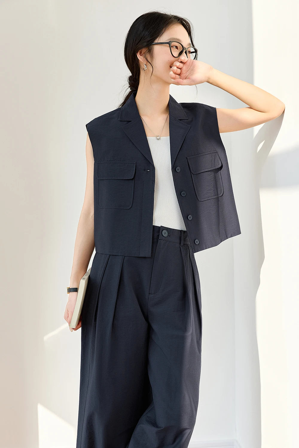 Woman in Mirage two-piece set with hand gently covering her lips — structured vest and trousers evoking composed strength. From Borcelleclothes.