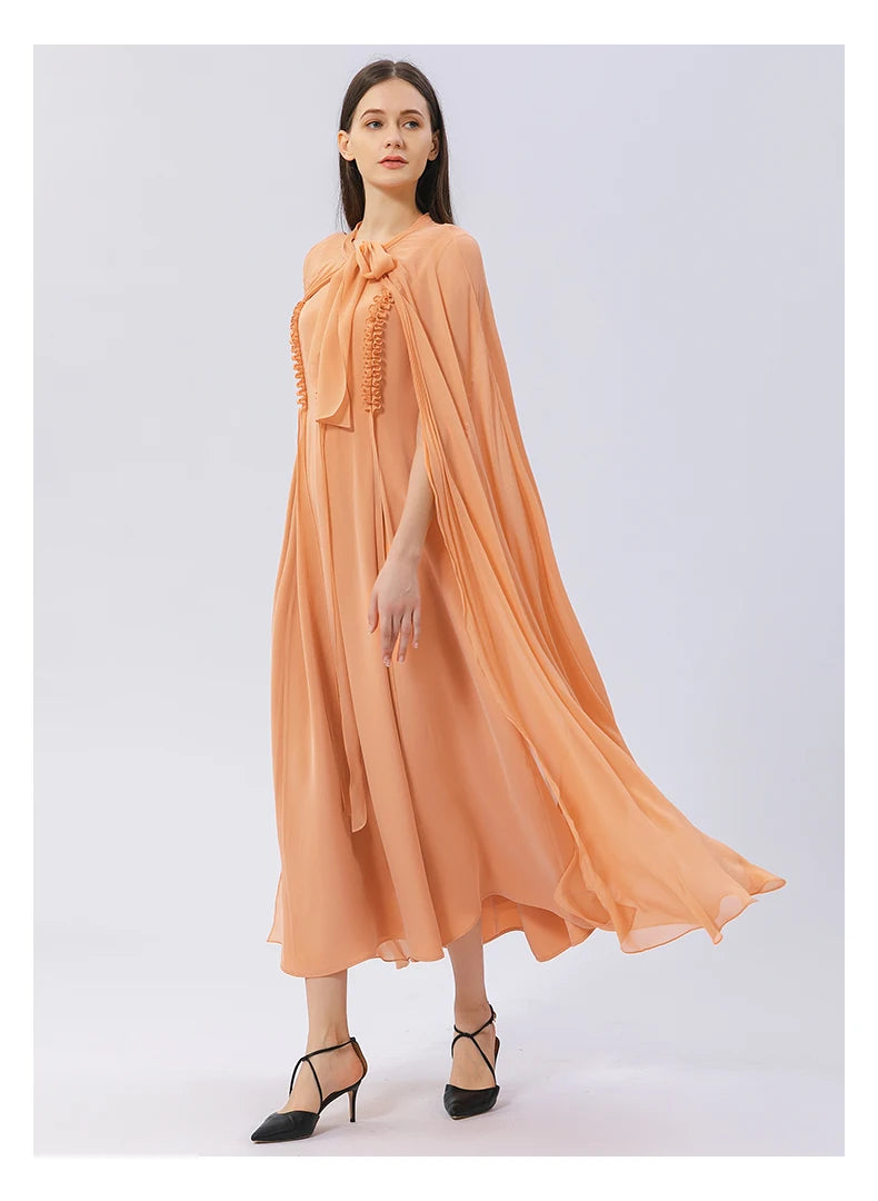 Model walking in side view, cape in motion revealing silk draping. From Borcelleclothes.