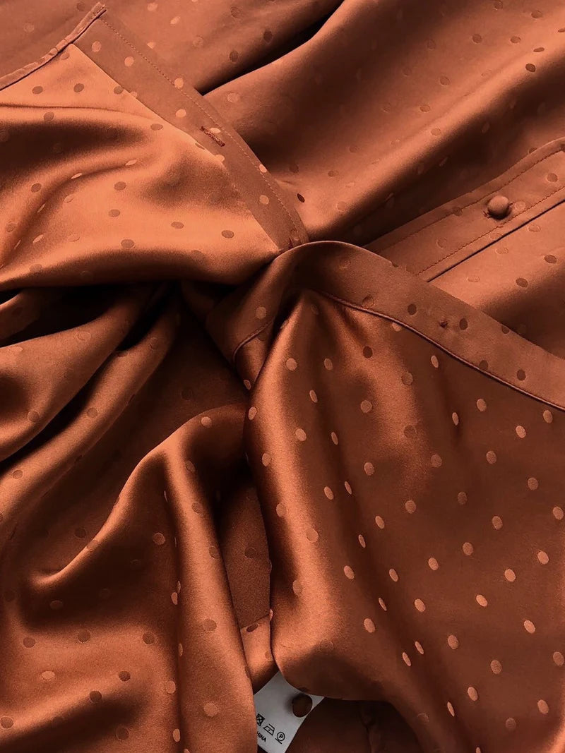 Detailed stitching and textured fabric on the part of the placket of a Women's Mulberry Silk Jacquard Shirt in Sienna, featuring a subtle dot pattern and center back pleat, crafted from luxurious 100% Mulberry silk for a refined and elegant look. From Borcelleclothes.