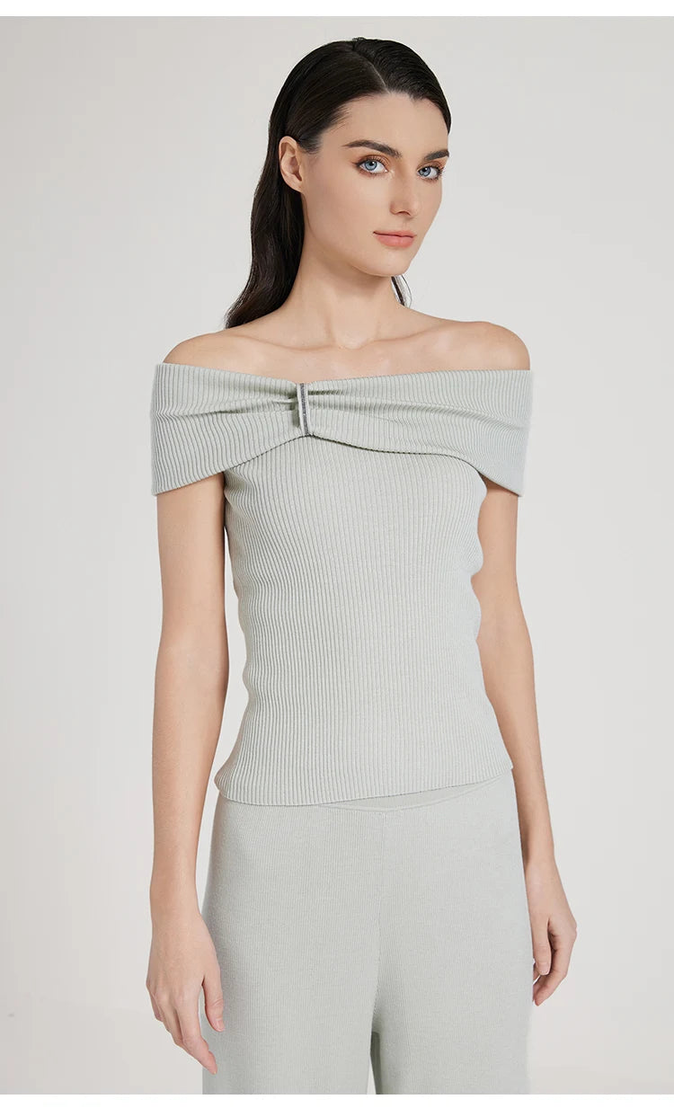 Model in Geyser-colored off-the-shoulder top, standing with arms straight down. From Borcelleclothes.