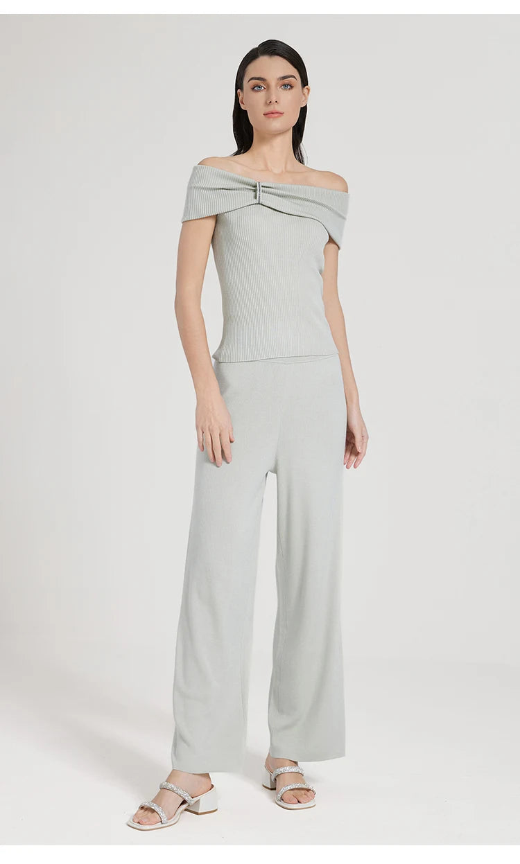 Full side view of the model wearing the Geyser-colored off-the-shoulder top, one foot angled outward. From Borcelleclothes.