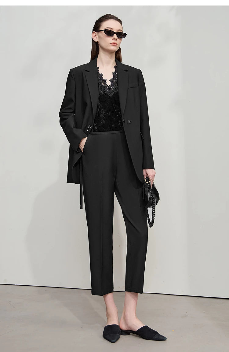Model in Onyx minimal blazer holding black bag, one hand in pants pocket – From Borcelleclothes.