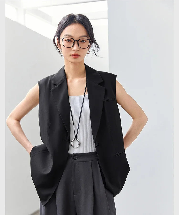 Woman in Onyx Sleeveless Blazer with hands behind her back. From Borcelleclothes.