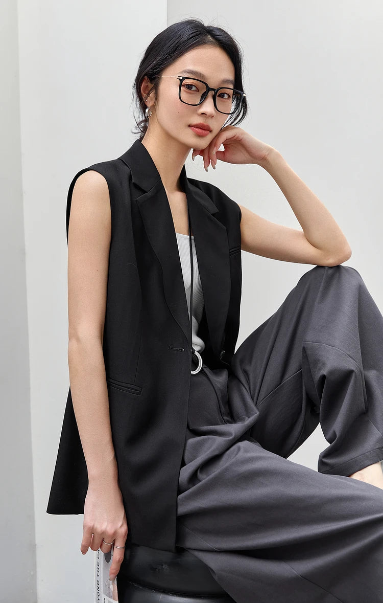 Woman in Onyx Sleeveless Blazer sitting on a chair with one foot lifted. From Borcelleclothes.