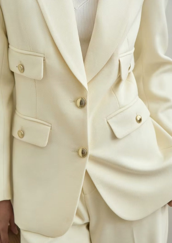 Middle section of the Sugar Cane blazer — two rows of flap pockets and a brass button create balance without excess. From Borcelleclothes.