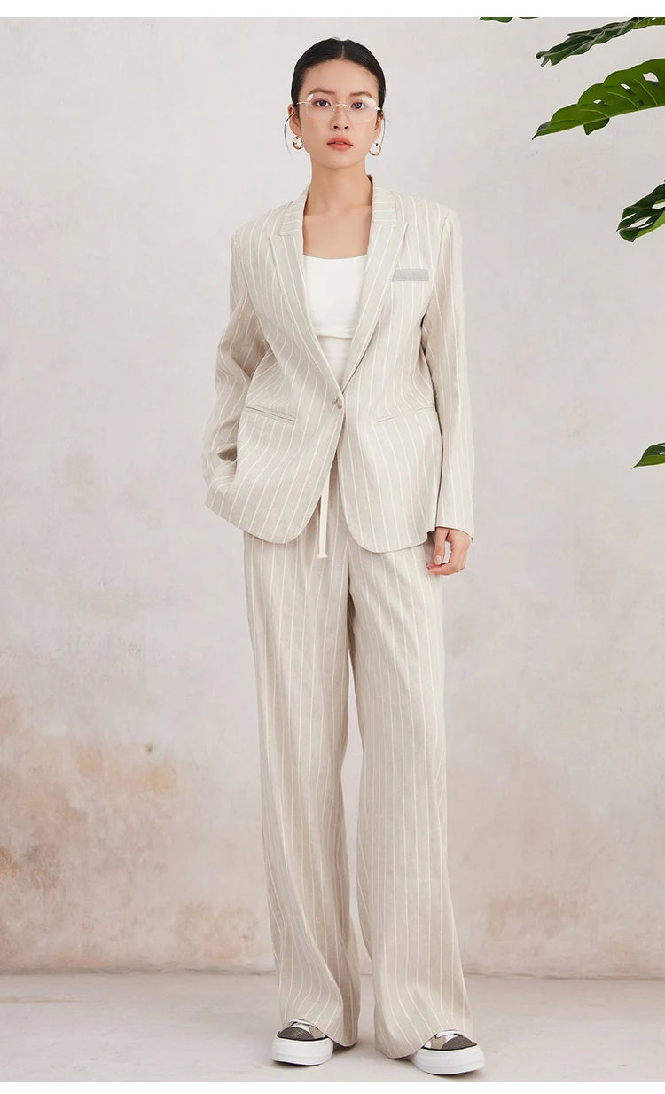 Full-length side view of the model in Pearl Bush striped blazer, one foot slightly forward. From Borcelleclothes.