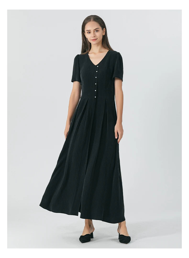 Model stands with hands straight, wearing the Jaguar-hued pinstripe silk dress with sculptural pleats and a structured wrap bodice. From Borcelleclothes.