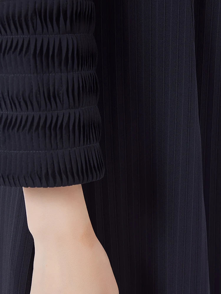 Detail of the long sleeve ending in a dense, horizontal tuck cuff, echoing the architectural lines of the lapels. From Borcelleclothes.