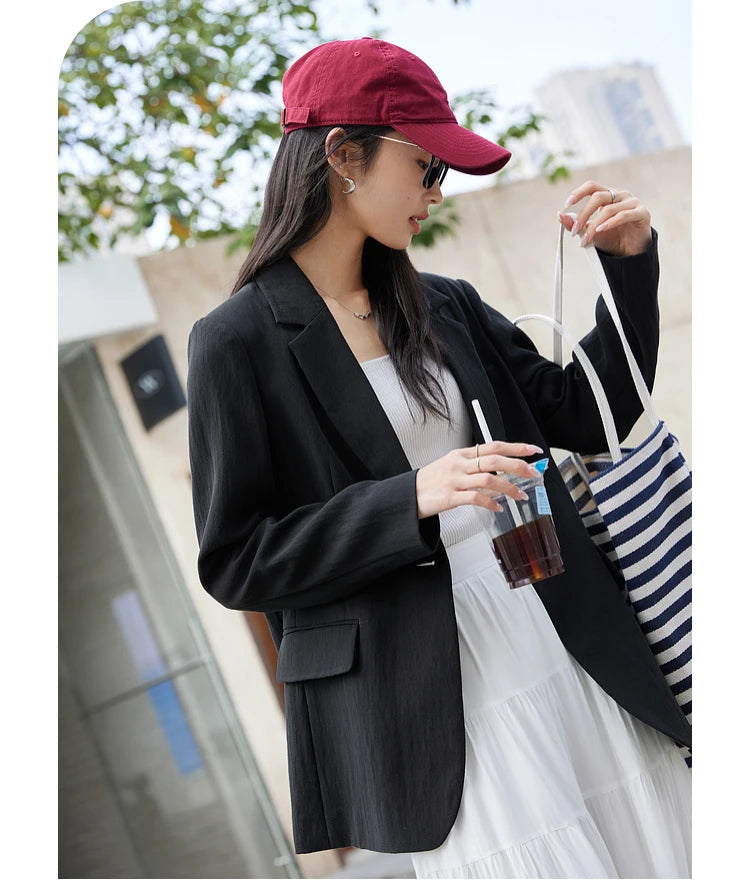 Woman in Onyx Urban Blazer holding a striped bag. From Borcelleclothes.