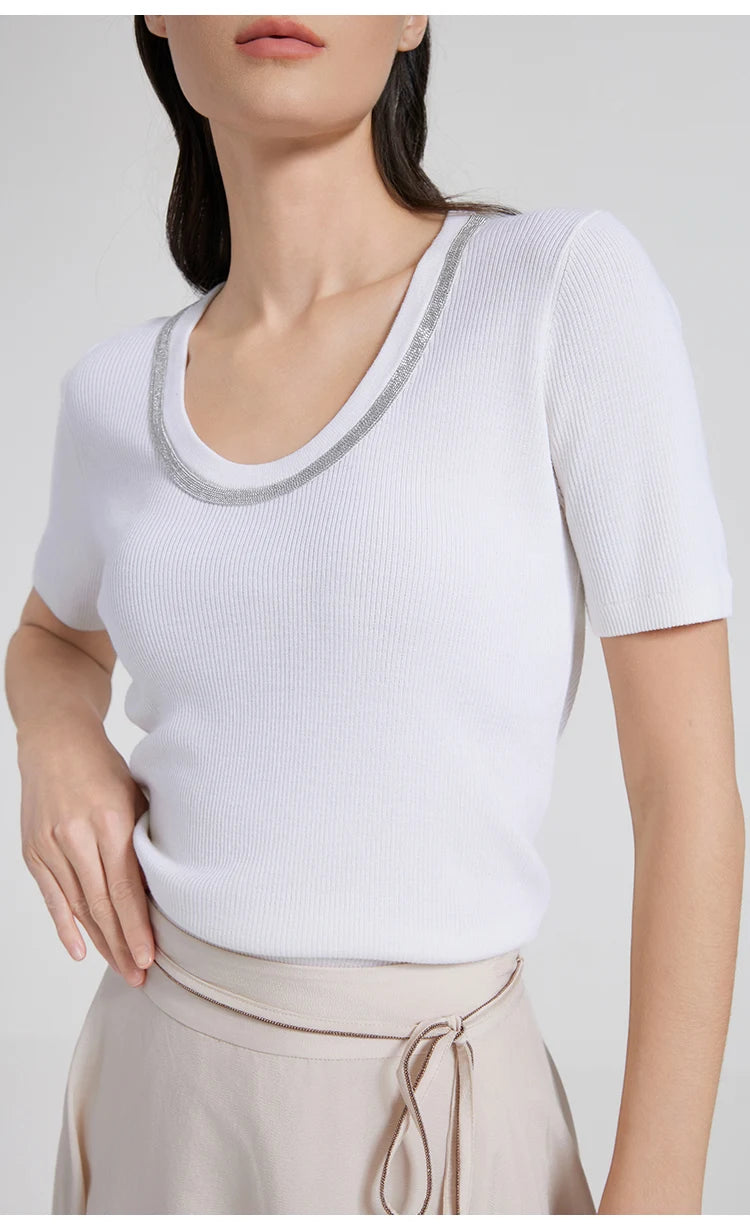 Woman in White Lilac top resting one hand at the waist, highlighting the slim silhouette and fluid knit texture. From Borcelleclothes.