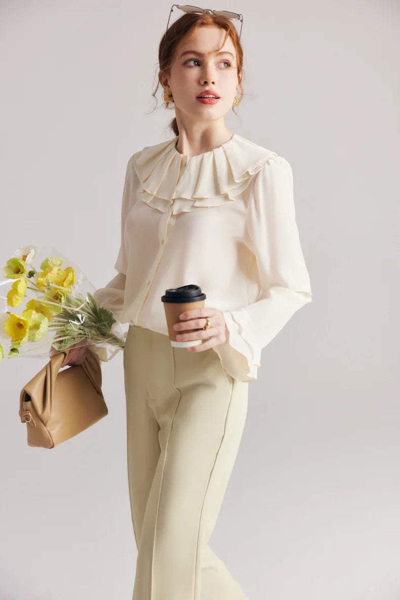 Model in the Women's Romantic Pearl Bush Silk Blouse with a cup of coffee, highlighting the elegant drape and double-layered flounce cuff. From Borcelleclothes.