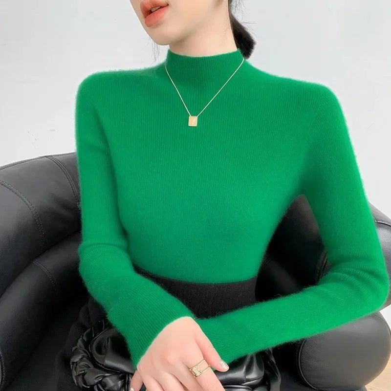 A model wearing the women's Saddle Sleeves Cashmere Sweater in Green Haze, sitting on the sofa. From Borcelleclothes.