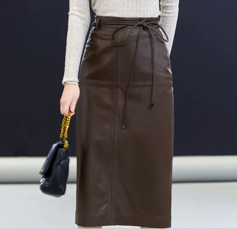 Model in Dark Rum leather skirt with one arm behind — the silhouette composed, the gesture quietly poised. From Borcelleclothes.