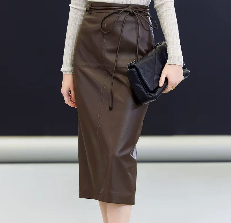 Woman wearing the sheepskin midi skirt in Dark Rum, holding a bag — a grounded silhouette defined by leather’s quiet structure. From Borcelleclothes.