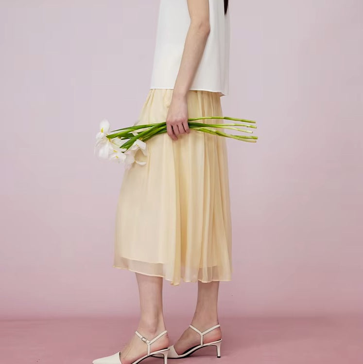 Model in Apricot White silk georgette skirt holding flowers, highlighting softness and flow. From Borcelleclothes.