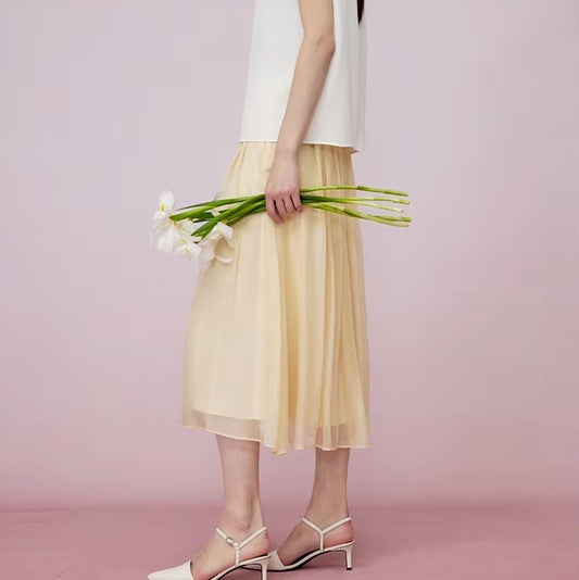 Model in Apricot White silk georgette skirt holding flowers, highlighting softness and flow. From Borcelleclothes.