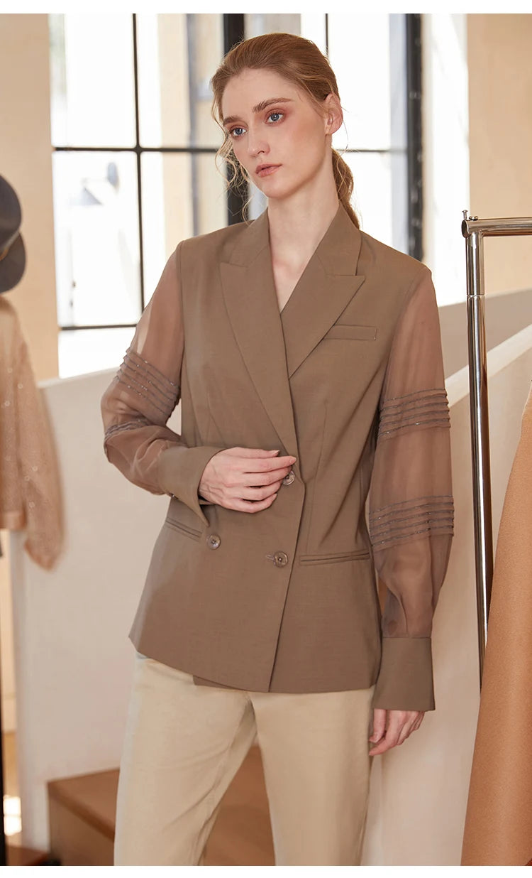 Women’s sheer-sleeved wool blazer in Milk Chocolate, model touching lapel. From Borcelleclothes.