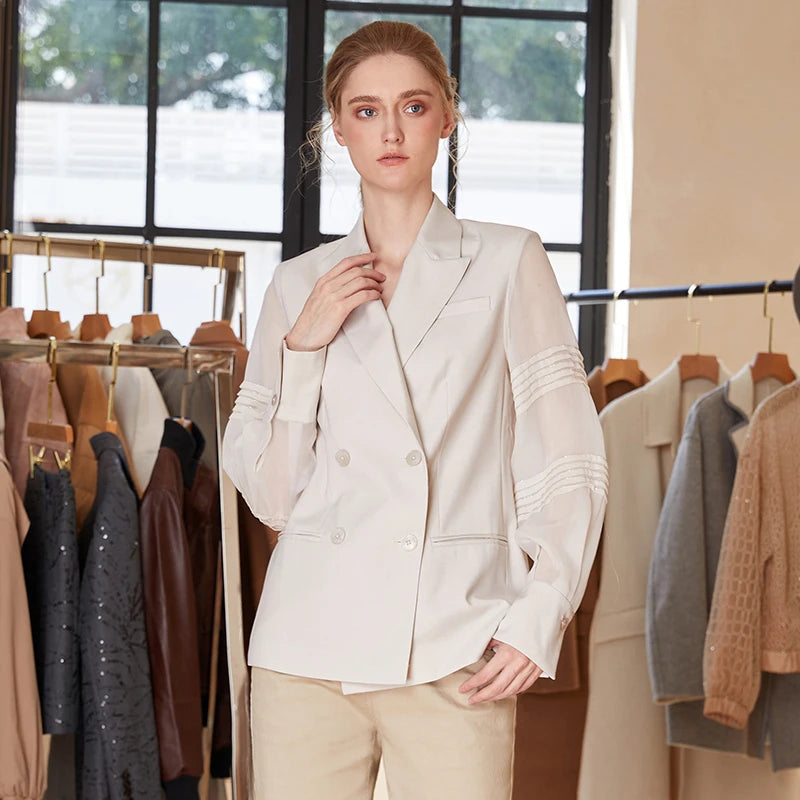 Women’s sheer-sleeved wool blazer in White Coffee, model touching pants pocket. From Borcelleclothes.