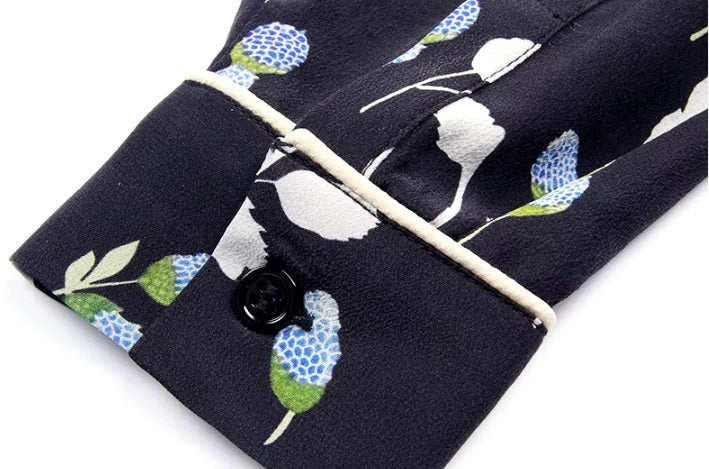 Detailed stitching and textured fabric on the piped cuff with the button of a women's silk shirt with berry-inspired print. From Borcelleclothes.