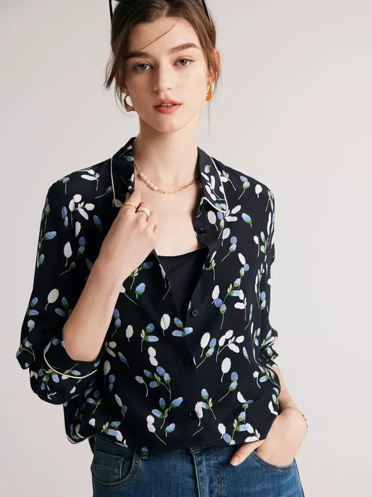 Model gently touching the collar of a women's silk shirt with berry-inspired print, showcasing the rounded collar with contrast piping. From Borcelleclothes.
