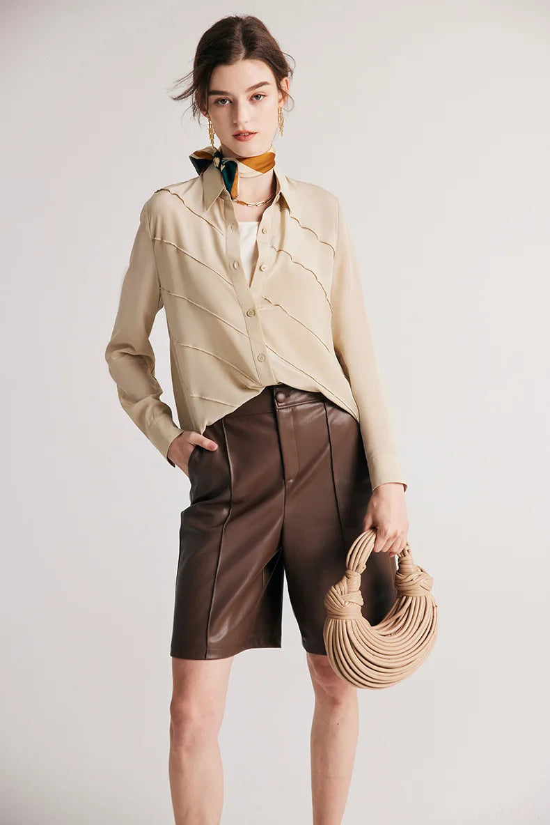 Model holding a bag while wearing silk shirt in Soft Amber. From Borcelleclothes.
