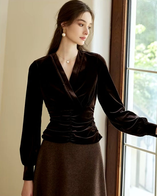 Model wearing Women's Silk Velvet Blouse in Coffee Bean with corset-inspired sculpted waist, standing by a window, exuding timeless elegance. From Borcelleclothes.
