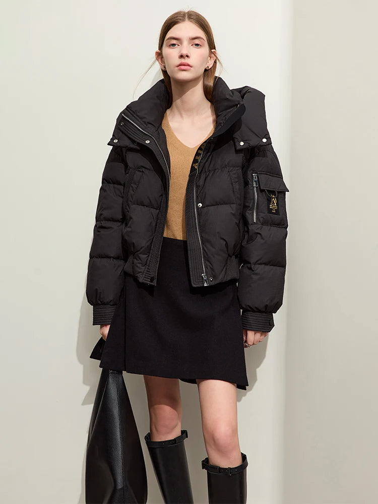 Model wearing the Onyx sleek down jacket and holding an oversized bag. Sleeve pocket with creative detail visible. From Borcelleclothes.