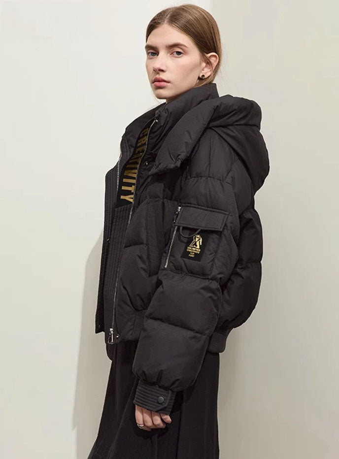 Women's sleek down jacket in Onyx with wrap collar, detachable hood, and utility sleeve pocket featuring creative detail. From Borcelleclothes.