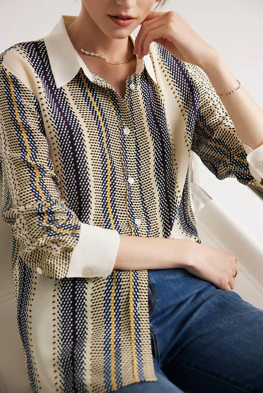Model touching the cream collar of a striped 3D geometric silk shirt, highlighting the contrast against the colorful geometric pattern. From Borcelleclothes.
