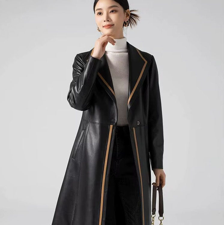 Women's Structured Leather Coat in Onyx with Warm Ochre Trim. Model touches her chin, mirroring the coat’s composed, thoughtful aesthetic. Borcelleclothes.