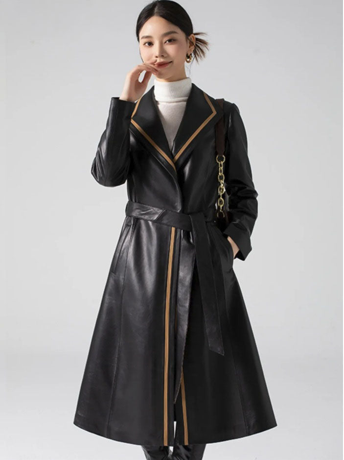 Women's Structured Leather Coat in Onyx with Warm Ochre Trim. Model lightly touches her face, emphasizing the coat’s quiet refinement and subtle contrasts. Borcelleclothes.