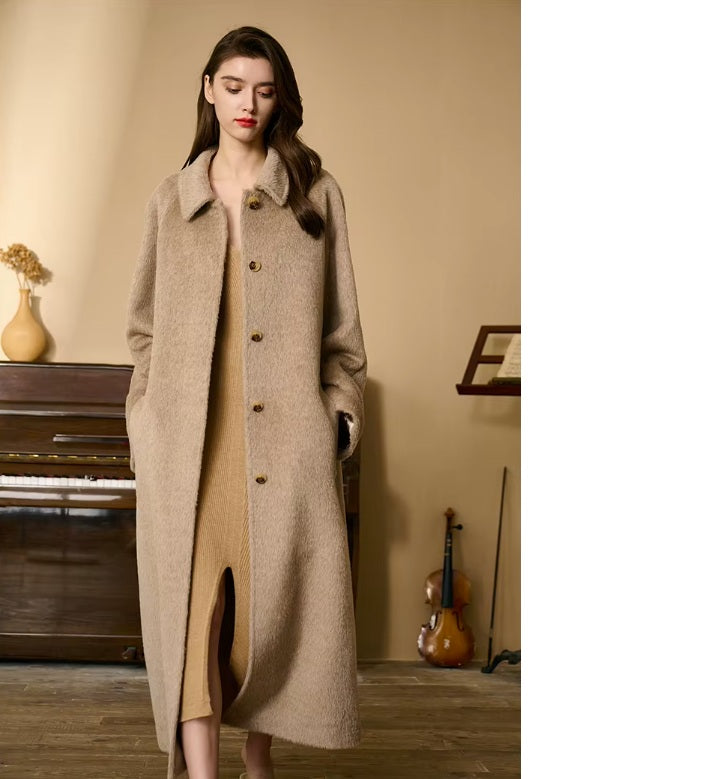 Model looking down while wearing the Pale Taupe Suri alpaca wool coat. From Borcelleclothes.