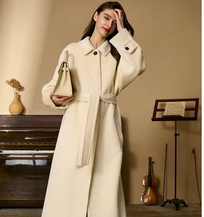 Model gently touching her hair while wearing the Pearl Bush Suri alpaca wool coat. From Borcelleclothes.