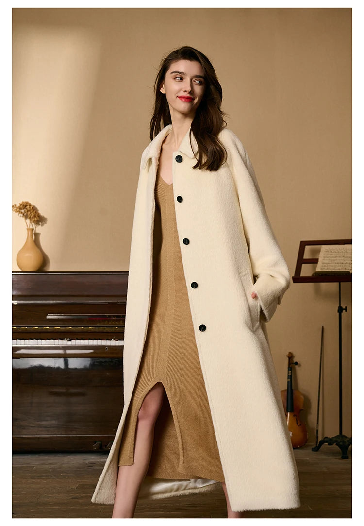 Model walking in profile while wearing the Pearl Bush Suri alpaca wool coat. From Borcelleclothes.
