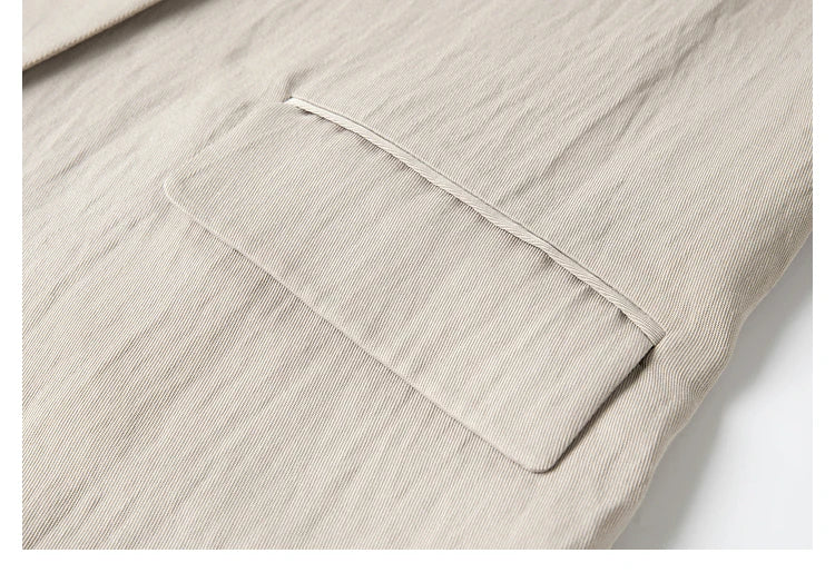 Close-up of side flap pocket on jacket — functional tailoring in calm neutral tone. From Borcelleclothes.