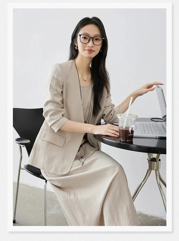 Model in Swiss Coffee set touching a notebook — effortless poise in structured jacket and light A-line dress. From Borcelleclothes.