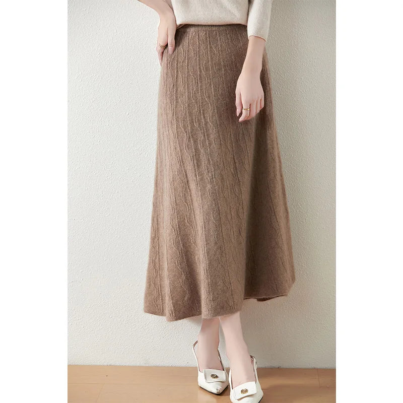 Textured merino wool skirt in Pale Taupe, model with crossed legs, highlighting mid-calf length and fluid A-line cut — From Borcelleclothes.