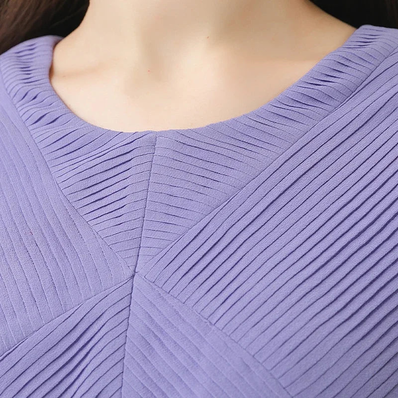Close view of the dress’s upper front, highlighting the geometric tuck details and the illusion of a layered vest. From Borcelleclothes.