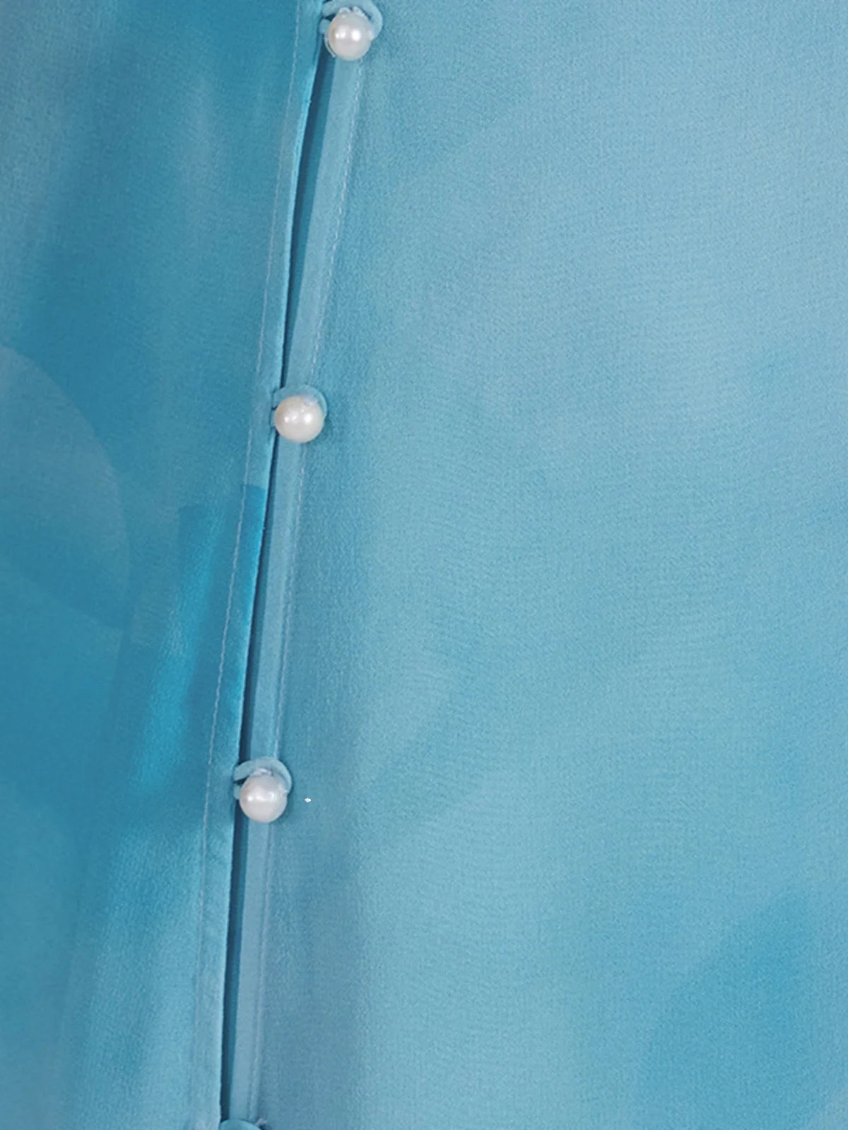 Close-up of the side slit with pearl-like buttons and silk loops on the chiffon layer of the Glacier ensemble. From Borcelleclothes.