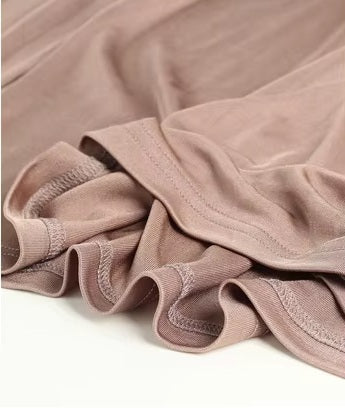 Detailed double-stitching and textured fabric on the bottom of a Women's Vintage-Inspired Silk Top in Rose Fog, featuring a V-neckline with delicate pleats and long sleeves in a Mulberry Silk blend. From Borcelleclothes.