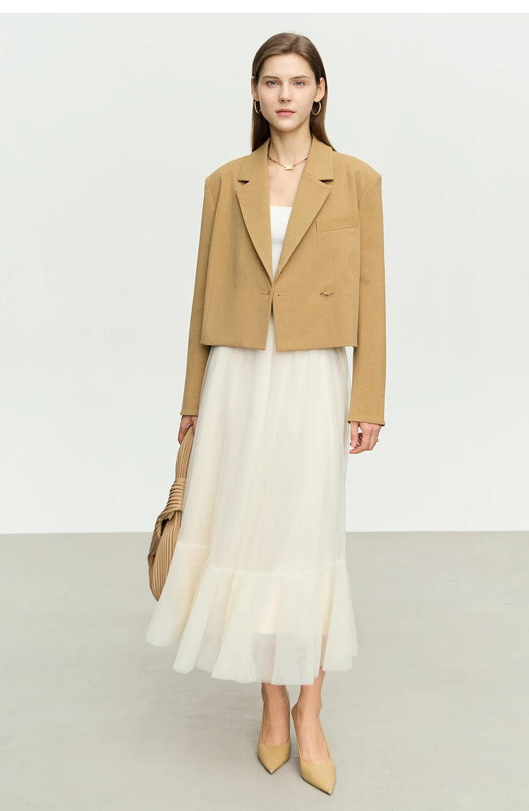 Women’s Wire Knot Detail Blazer in French Beige, worn unbuttoned over a white chiffon dress. From Borcelleclothes.