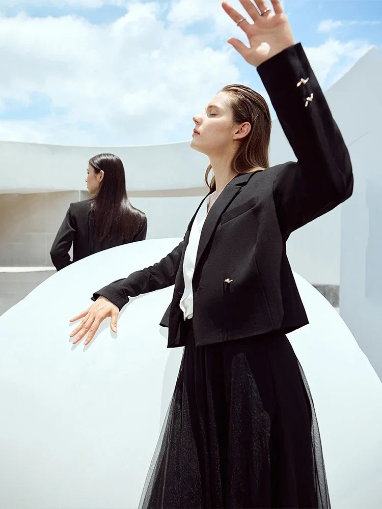 Women’s Wire Knot Detail Blazer in Onyx, model leaning with arm on a white sphere. From Borcelleclothes.